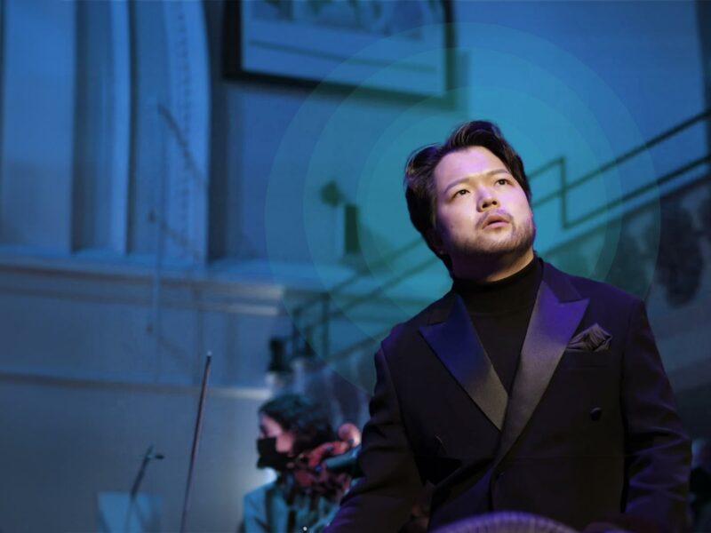 Person on stage wearing a suit looking to the side