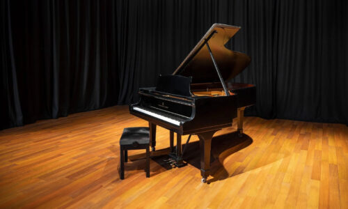 Grand piano in the centre of a room with curtains in the background