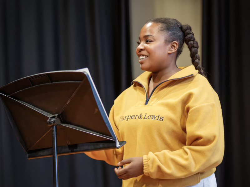Person looking to the side in front of a music stand smiling