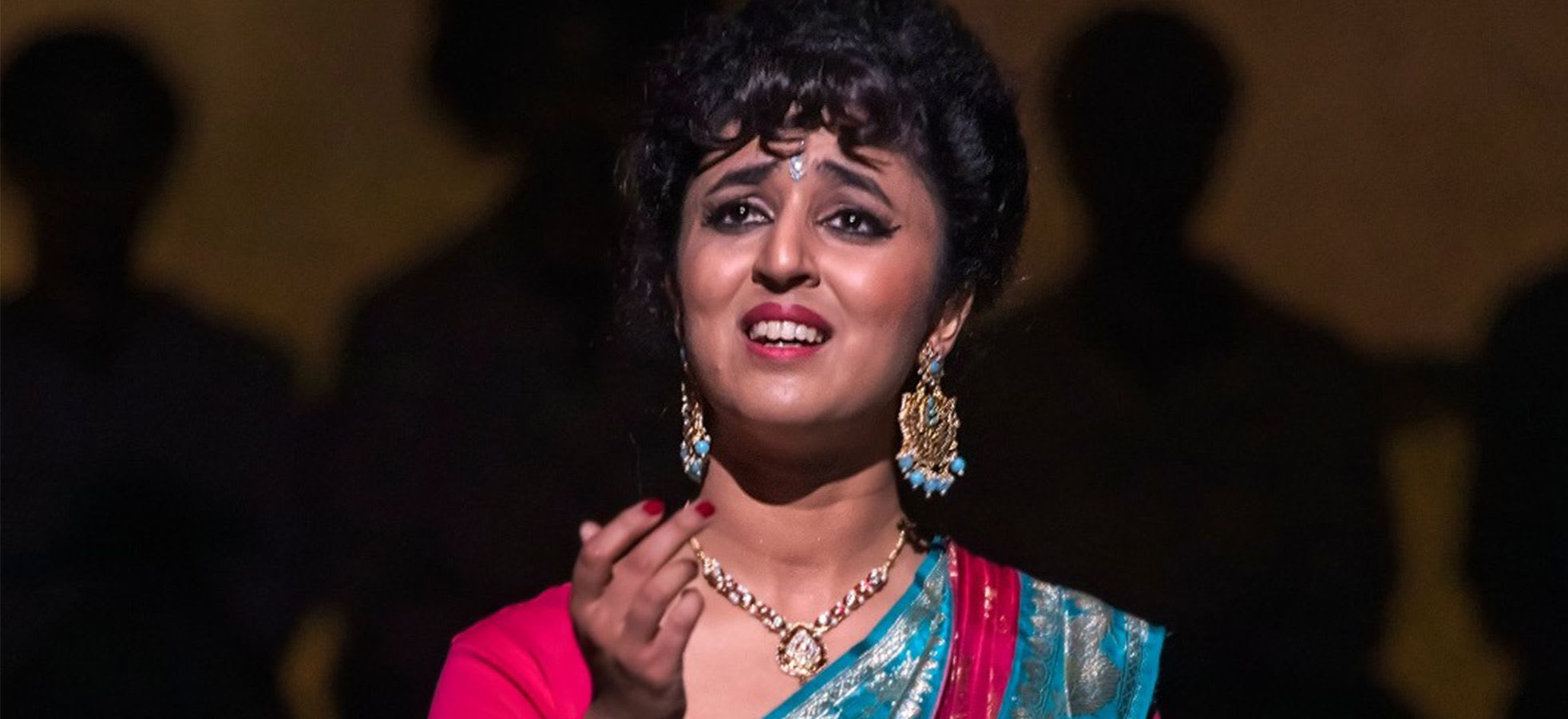 British Indian soprano & dancer Natasha Agarwal on stage wearing a colourful saree and earrings