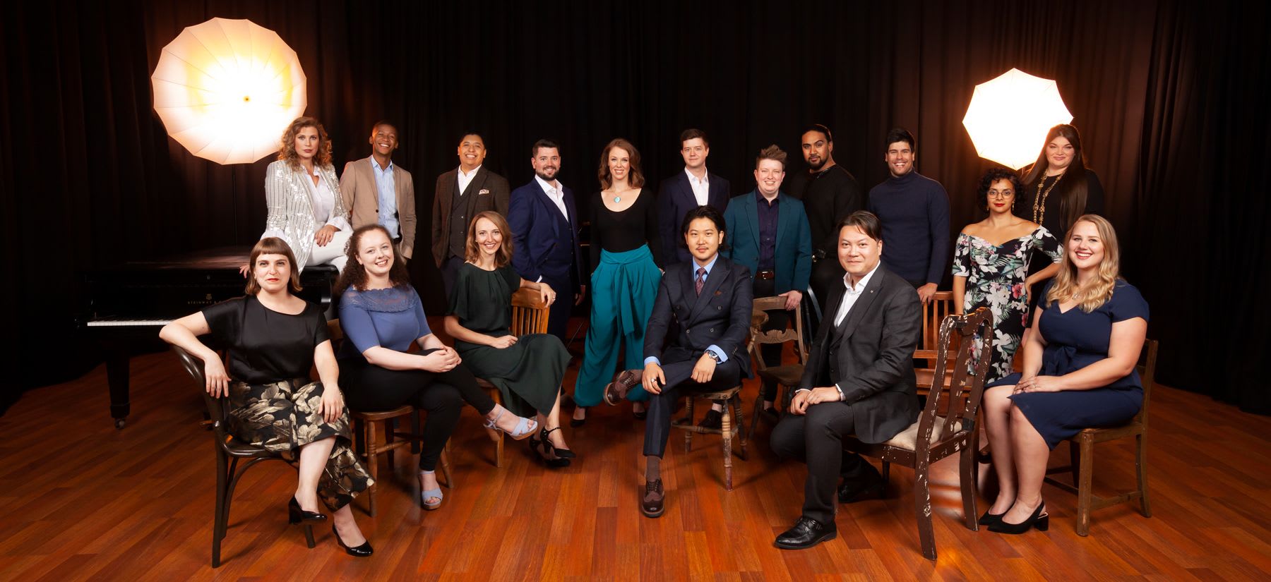Group of Young Artists smartly dressed sat on chairs in a row