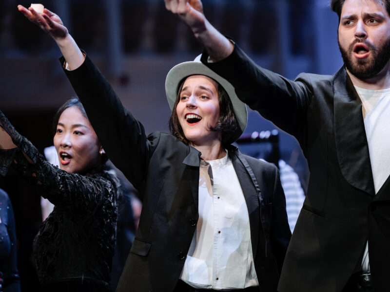 Three people stood in a row with their arms up in the air