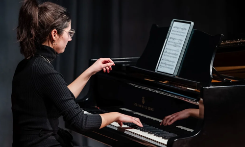 Person playing piano reading sheet music