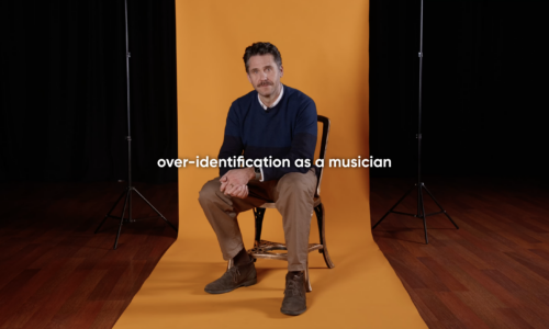 Opera singer and therapist Ed Lyon in front of an orange paper backdrop. text reads over identification as a musician
