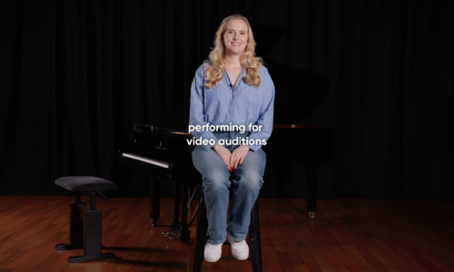 Nancy Holt - National Opera Studio Alum discussing how to perform for video auditions, sat on black stool in front of black piano and background