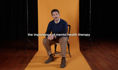 The importance of Mental Health Therapy - Ed Lyon - National Opera Studio alum and therapist in front of an orange backdrop