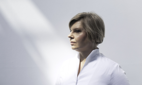Lada Vaselova in a white shirt looks to the left in front of a white background