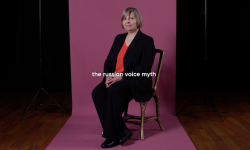 Lada Valesova sits on a chair in front of a maroon paper background, text reads The Russian Voice Myth