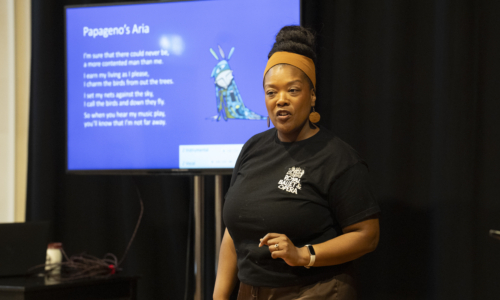 Delivering Opera in Education image of woman presenting an aria in front of a board, wearing a royal ballet and opera t shirt